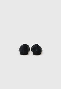 Ballerines noires en daim avec un bout pointu et un petit talon. Texture lisse et design minimaliste, vues de l'arrière.
