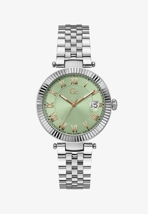 Reloj de acero inoxidable plateado con un dial verde texturizado, números romanos dorados, visualización de la fecha y una pulsera de eslabones. Bezel acanalado notable.