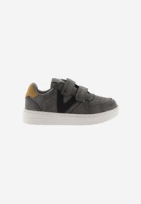 Zapatilla de piel gris con acentos negros y una pestaña amarilla en el talón. Presenta dos correas de Velcro y una puntera perforada. Suela de goma blanca.