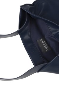Navy blue leather tote bag with smooth texture, open top, and two handles. Interior features a fabric lining and a brand label.