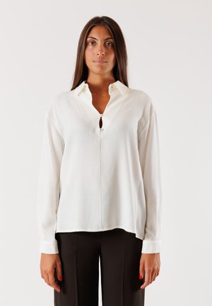 Camicia bianca a maniche lunghe con colletto, dotata di una chiusura parziale a bottoni e orlo dritto. Realizzata in un tessuto leggero con una texture morbida.