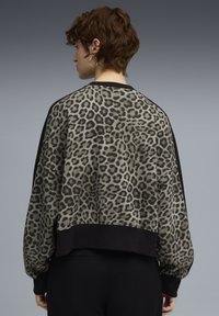 Pullover con stampa leopardata e design cropped, composto da un tessuto strutturato, dettagli neri su maniche e fondo, e collo rotondo.