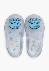 Translucent plastic sandals featuring a blue cartoon face on the top, with a white interior adorned with blue marine-themed illustrations.