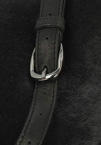 Cintura in pelle nera con fibbia metallica, caratterizzata da una superficie liscia e cuciture curate, posizionata su uno sfondo scuro e texture.
