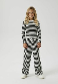 Zwart-wit gestreepte lange mouw top en wijde broek, met een trekkoord taille en geribbelde textuur, gecombineerd met witte schoenen.