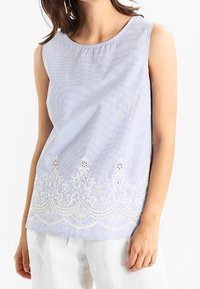 Top senza maniche a righe blu e bianche con collo rotondo e bordo decorativo in pizzo bianco lungo l'orlo, con motivi floreali.