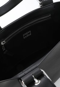 Schwarze Ledertasche mit silbernem Reißverschluss und Logoetikett im Inneren. Verfügt über ein geräumiges Hauptfach und stabile Griffe.