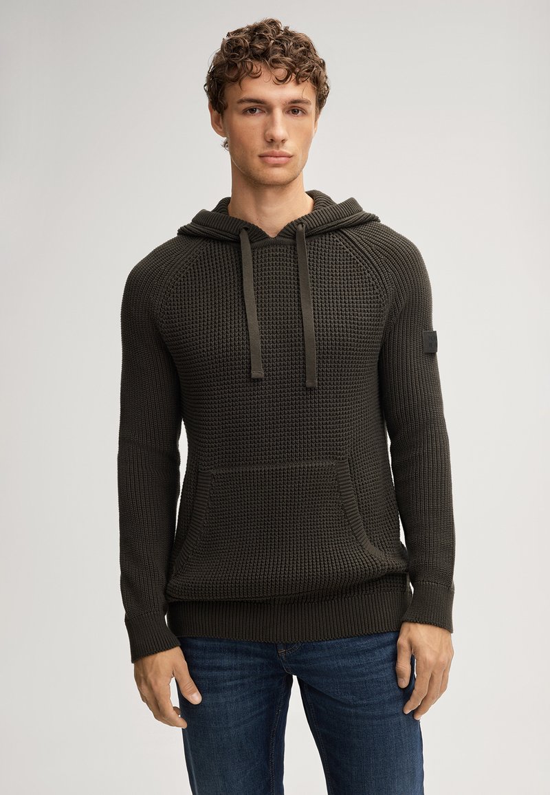 Groene, gestructureerde hoodie met een zak aan de voorkant, een trekkoordcapuchon en geribbelde manchetten. Bevat een klein patchdetail op de mouw.