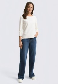 White three-quarter sleeve top paired with wide-leg dark blue jeans and white sneakers, featuring a simple design and relaxed fit.
