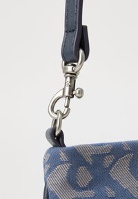 Borsa di stoffa blu con un motivo testurizzato, dotata di una chiusura in metallo argentato e un attacco in pelle blu scuro.
