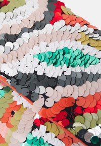 Pochette en sequins avec des sequins ronds et carrés de différentes couleurs : rouge, vert, noir, blanc et beige, sur une base en tissu noir contrastée.