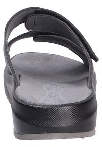 Tongs noires avec deux sangles ajustables, semelle intérieure texturée et une épaisse semelle. Présente une semelle intérieure grise lisse et légèrement rembourrée.