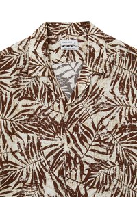 Camicia a maniche corte, con vestibilità rilassata, di colore crema con un motivo di foglie marroni e beige, dotata di chiusura con bottoni e texture del tessuto morbida.