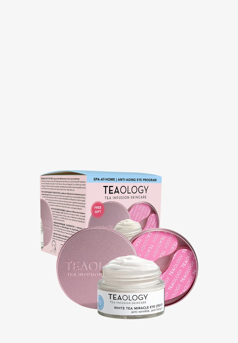 Słoiczek kremu do oczu Teaology White Tea Miracle z białym kremem, przezroczystym, szklanym dnem i różową, okrągłą pokrywką. Pudełko z niebieskim i różowym tekstem, na którym znajduje się napis "Prezent gratis".