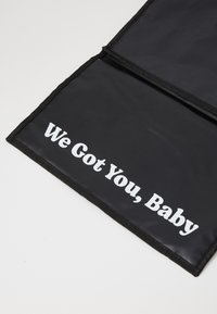 Μαύρο�ς φάκελος με γυαλιστερή υφή που φέρει το κείμενο "Σε έχουμε, μωρό" με έντονη λευκή γραφή κατά μήκος της κάτω άκρης. Χωρίς πρόσθετα διακοσμητικά στοιχεία.