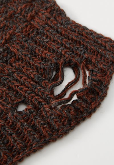 Tecido de malha em castanho escuro e cinza com um padrão solto e texturizado. Apresenta um buraco irregular, revelando pontas de fio desfiadas.