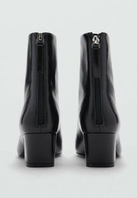 Bottines en cuir noir avec un bout carré et un talon bloc. Présente une fermeture éclair visible à l'arrière et une texture lisse et brillante.