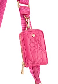 Bolso mini de tela acolchada rosa con herrajes dorados, con un patrón de flores y una correa desmontable. Cierre de cremallera con un detalle de costura destacado.