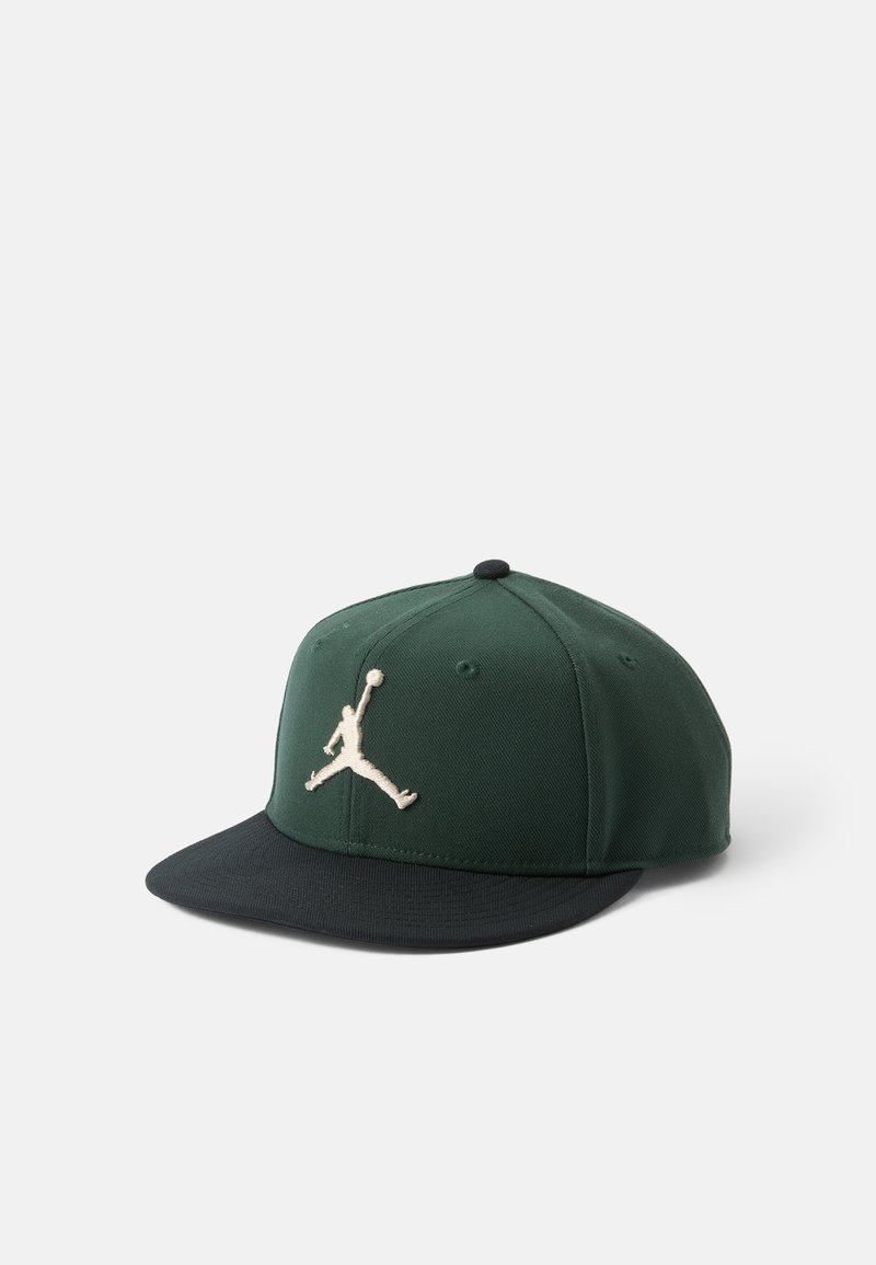 Zelená a čierna čiapka s pevným šiltom, na prednej strane s vyšitým logom Jumpman v svetlej béžovej farbe. Materiál z bavlnenej zmesi.