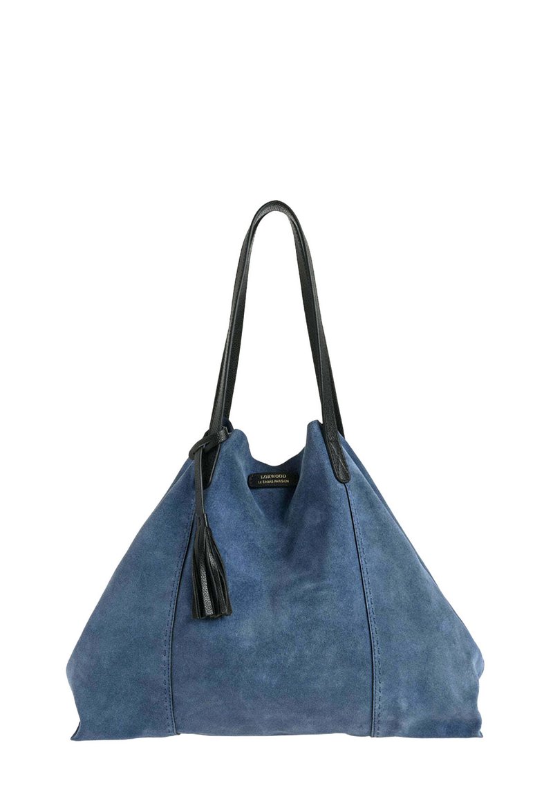 Sac fourre-tout en daim bleu avec de longues poignées en cuir noir et un détail à pompon, arborant une petite étiquette de la marque près du centre supérieur.