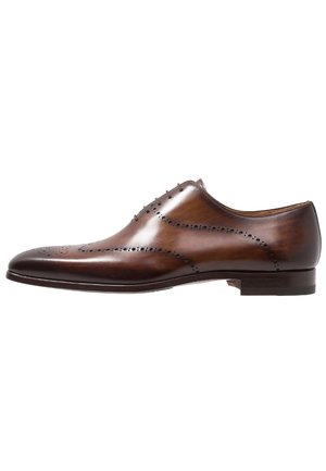 Chaussure habillée marron en cuir pour homme avec perforations brogue et fermeture à lacets, présentée en profil latéral sur fond blanc.