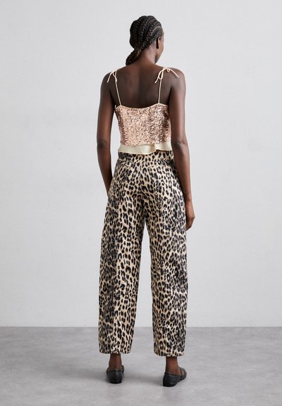 Top cropped de lantejoulas em rosa dourado, combinado com calças largas de padrão leopardo. O top possui alças ajustáveis e uma cintura em cetim.