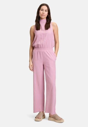 Lyserød ærmeløs jumpsuit med høj hals, elastisk talje og brede ben, lavet af et let stof. Modellen bærer neutrale slip-on sko.