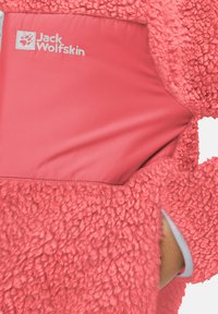 Giacca in fleece di un vivace corallo, con un'esterno testurizzato, una fodera interna morbida e un logo ben visibile. Include un'apertura per tasca laterale.