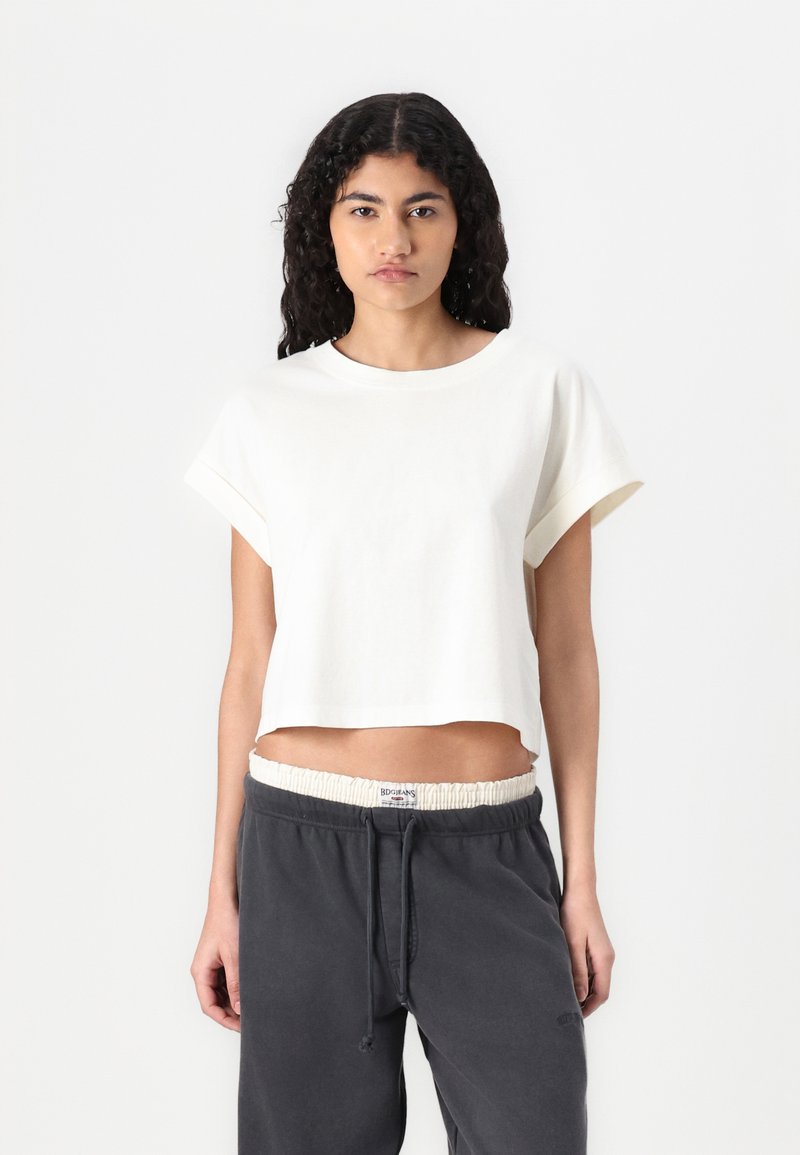 Weißes, kurzärmliges Cropped-T-Shirt aus weichem Baumwollmaterial, kombiniert mit dunkelgrauen Sweatpants mit Kordelzug und gerafftem Bund.