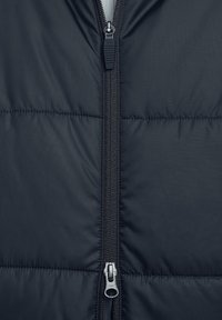 Marineblauer Puffer-Jacke mit Halbreißverschluss, ausgestattet mit gesteppten Abschnitten, glatter Textur und silbernem Reißverschluss.
