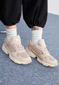 Beiga sportskor med en blandning av mocka och mesh, med en tjock, krämfärgad sula och tonala snörning. Randiga vita och gröna strumpor kompletterade looken.