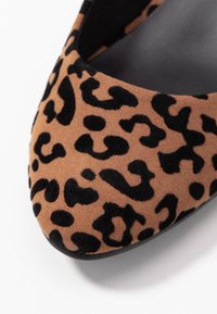 Leopard-print flat shoe featuring a soft brown and black suede exterior, pointed toe design, and smooth black interior.