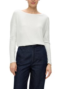 Weißes Langarmshirt mit U-Boot-Ausschnitt, kombiniert mit dunklen Jeans. Der Stoff ist glatt und leicht.