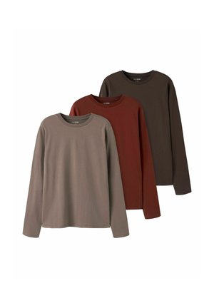 Trois chemises unies à manches longues avec col rond en taupe, rouille et marron foncé, disposées en chevauchement sur un fond blanc.