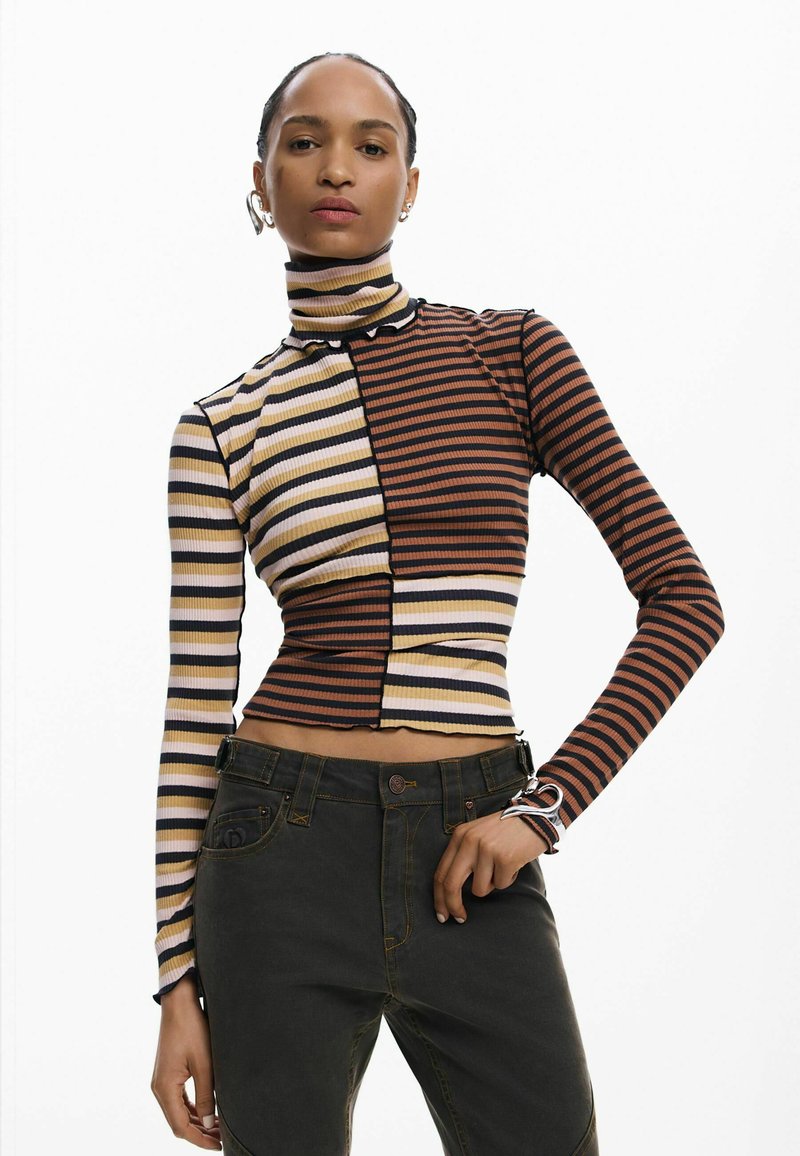 Beežide, bordoopunaste ja mustade triipudega kõrge kaelusega top, millel on istuv lõige, segatud mustrid ja lühike lõige. Stiilitud tumedate teksadega.