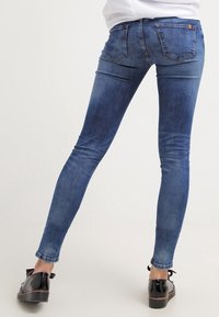 Smala jeans i ljusblå denim. Har en hög midja, bakfickor och en jämn textur. Bärs med svarta skor.