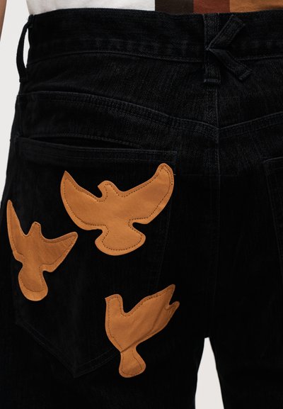 Μαύρο τζιν παντελόνι με τρία ταμπά δερμάτινα πουλερικά κεντήματα στις πίσω τσέπες, με υφή και εφαρμοστή μέση.