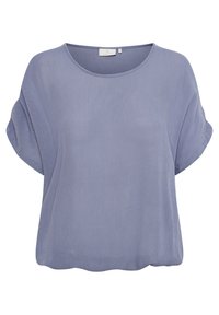 Blouse courte à manches courtes de couleur violet clair avec un col rond et une coupe ample, présentant une texture subtile et une étiquette de vêtement à l'intérieur du col.