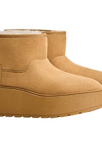 Vastag gumitalpú, világosbarna velúr bokacsizmák, puha fehér bélés látható a tetején.