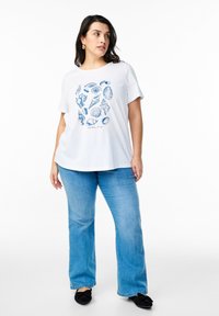 White cotton t-shirt featuring a blue seashell graphic and the word "SALT." Paired with light blue flared jeans and black flats.