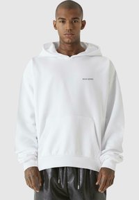 White hooded sweatshirt made of cotton blend, featuring a front pocket, ribbed cuffs, and a small printed logo on the chest.