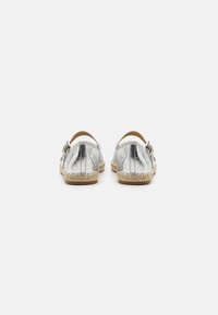 Silver metallic espadrilles with a woven jute sole, featuring a back strap and buckle detail. Smooth texture and rounded toe design.