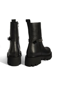 Black leather ankle boots with a chunky, textured sole, zip closure, and a decorative strap accent. Smooth finish and sturdy construction.