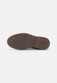 Suela de zapato de goma marrón con un patrón de zigzag y una marca en relieve, diseñada para tracción y durabilidad.