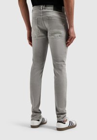 Grijs denim jeans met een slim fit, met twee achterzakken en minimale stikdetails, gecombineerd met witte schoenen.
