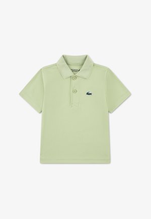 Helehelesinine polo-särk pehmest kangast, klassikalise krae, kolme nööbi ja väikese õmmeldud krokodillilogoga rinnal.