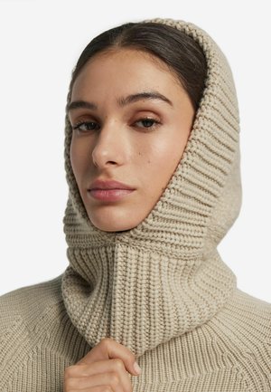 Beżowa dzianinowa bluza z kapturem z wysokim golfem i prążkowaną fakturą. Dopasowany krój z grubym, przytulnym wzorem dzianiny.