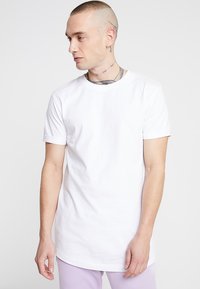 Weißes Baumwoll-T-Shirt mit kurzen Ärmeln, rundem Ausschnitt und lockerer Passform. Auf einer Figur vor einem schlichten Hintergrund präsentiert.