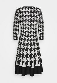 Sukienka dzianinowa w czarno-białą kratę w guziki, z rękawami o długości trzech kwart, rozkloszowanym dołem i okrągłym dekoltem.