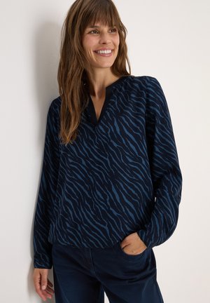 Blusa a maniche lunghe blu navy con un motivo a strisce zebrate blu, caratterizzata da un scollo a V e una vestibilità rilassata. Tessuto morbido con una texture liscia.